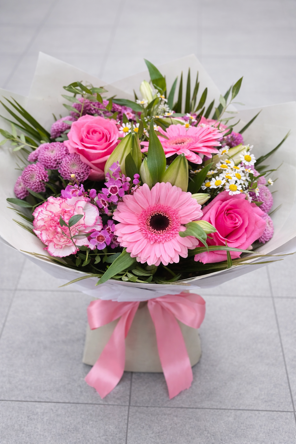 Bouquet of pink flowers with a pink ribbon on a light gray background