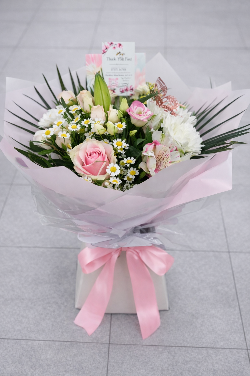 Bouquet of flowers with pink ribbon on a light gray background