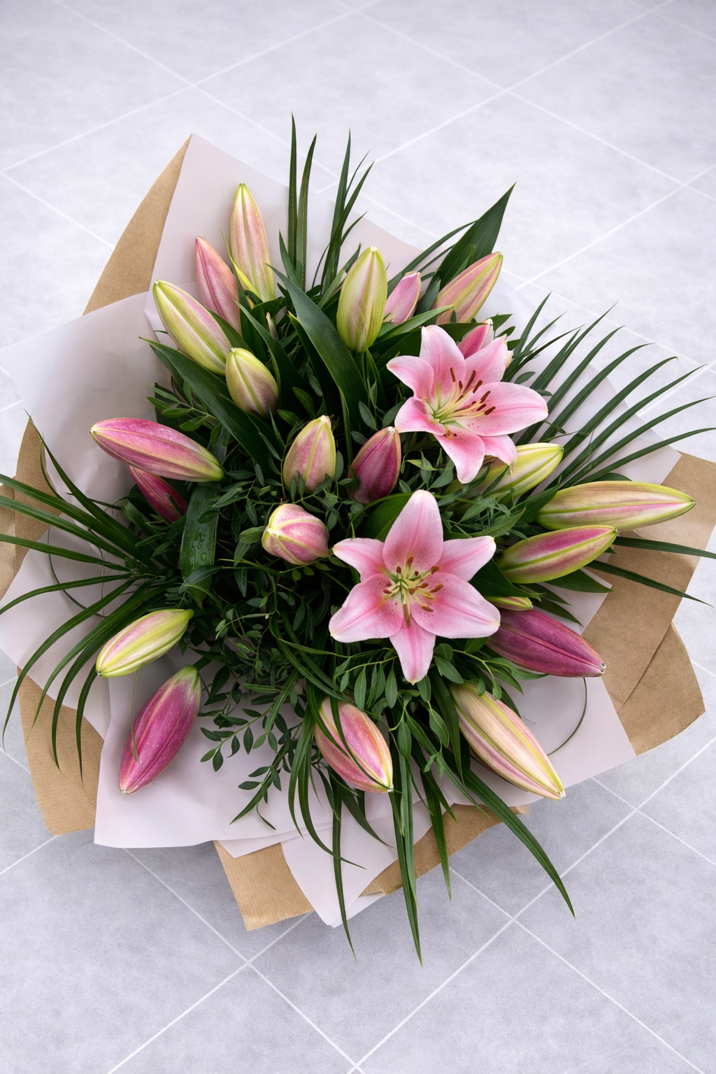 Bouquet of pink and lilies with green leaves on a light gray background