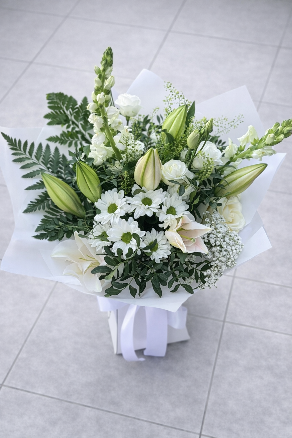 Bouquet of white and green flowers on a light grey floor