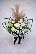 Bouquet of white flowers with greenery and dried grasses on a light grey tiled background