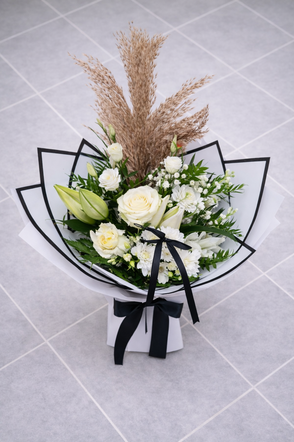Bouquet of white flowers with greenery and dried grasses on a light grey tiled background